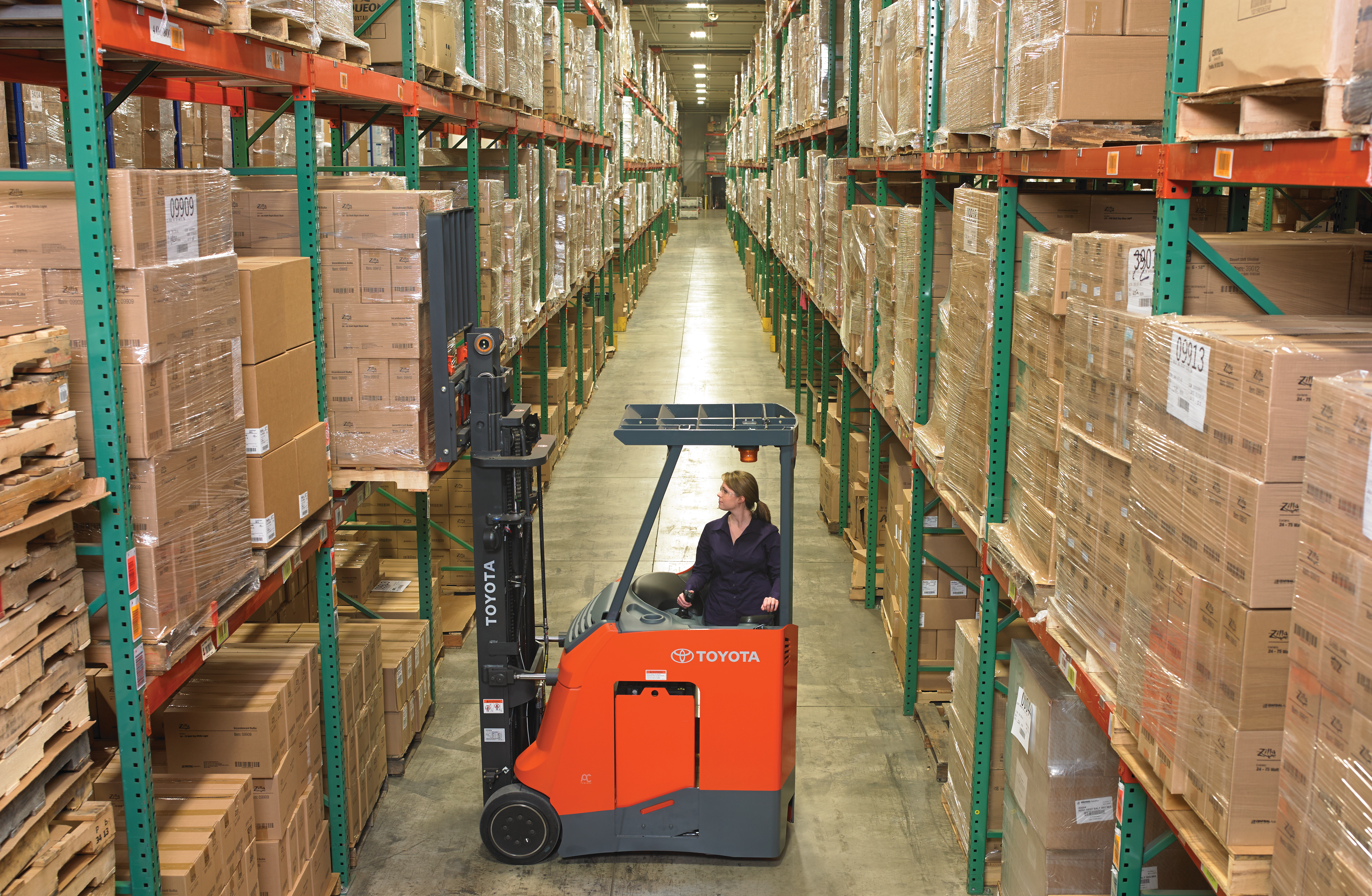 Toyota stand up riding forklift being used in a warehouse